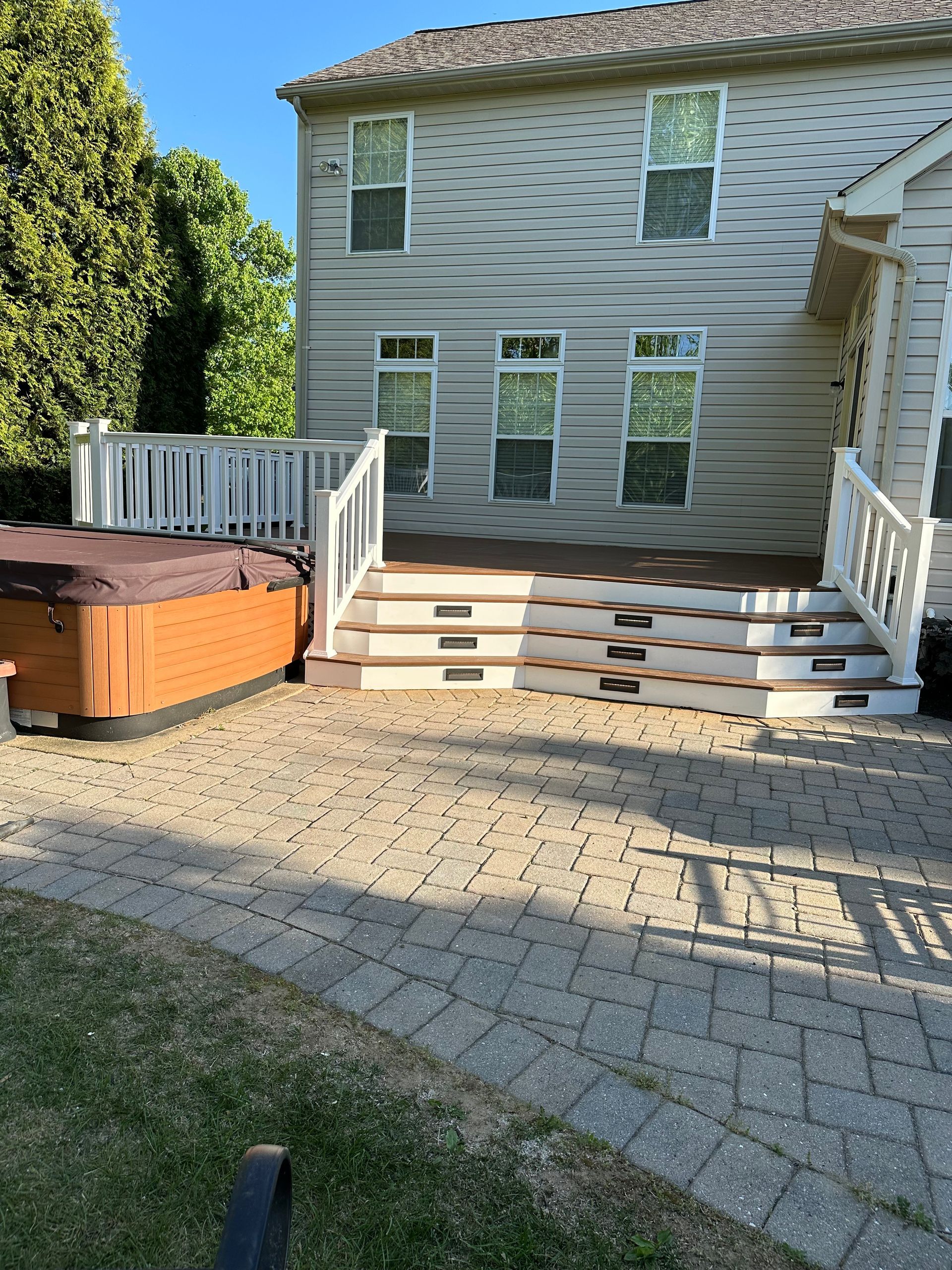 A hot tub is sitting on a patio in front of a house.