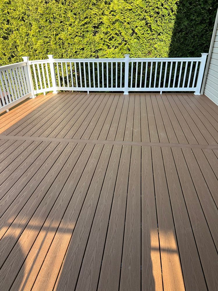 A wooden deck with a white railing and trees in the background.