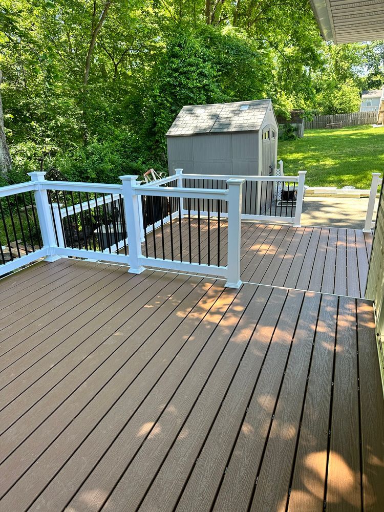 A wooden deck with a white railing and a shed in the background.