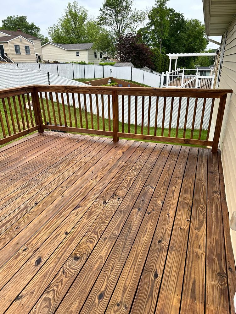 A wooden deck with a railing and a view of a backyard.