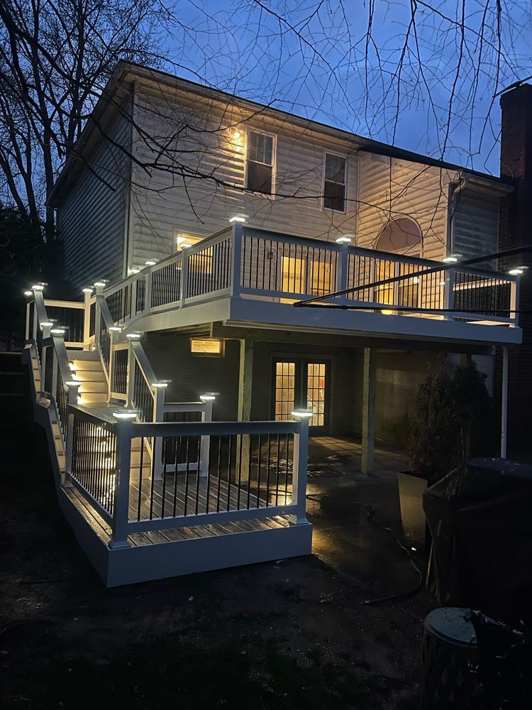 A house with a large deck and stairs is lit up at night.