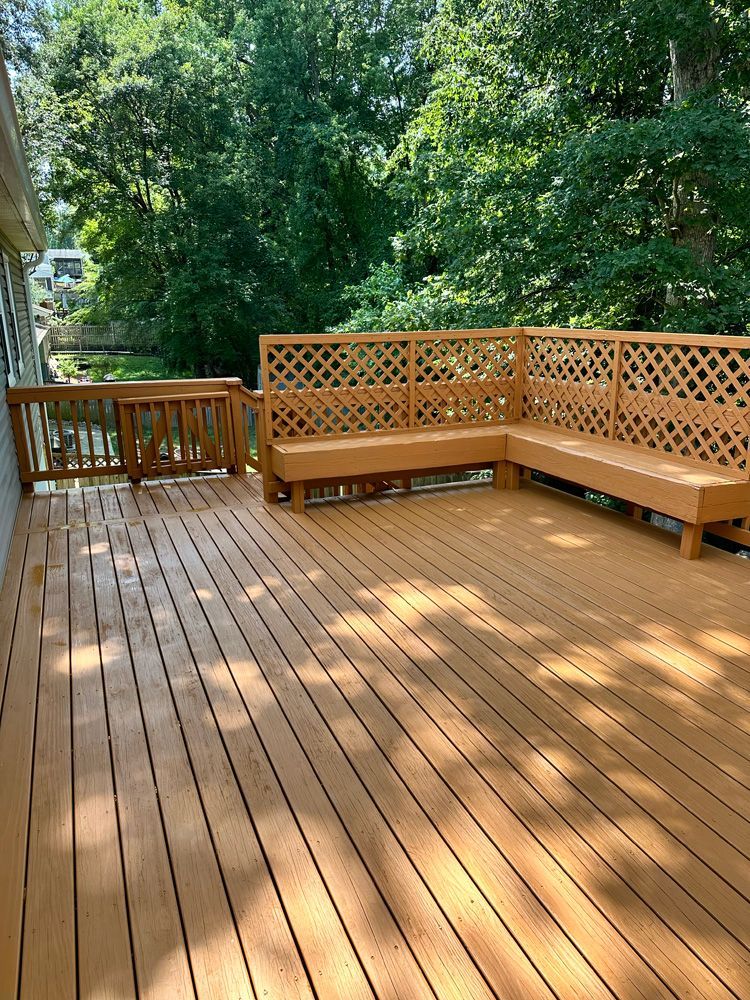 A large wooden deck with a couch on it surrounded by trees.