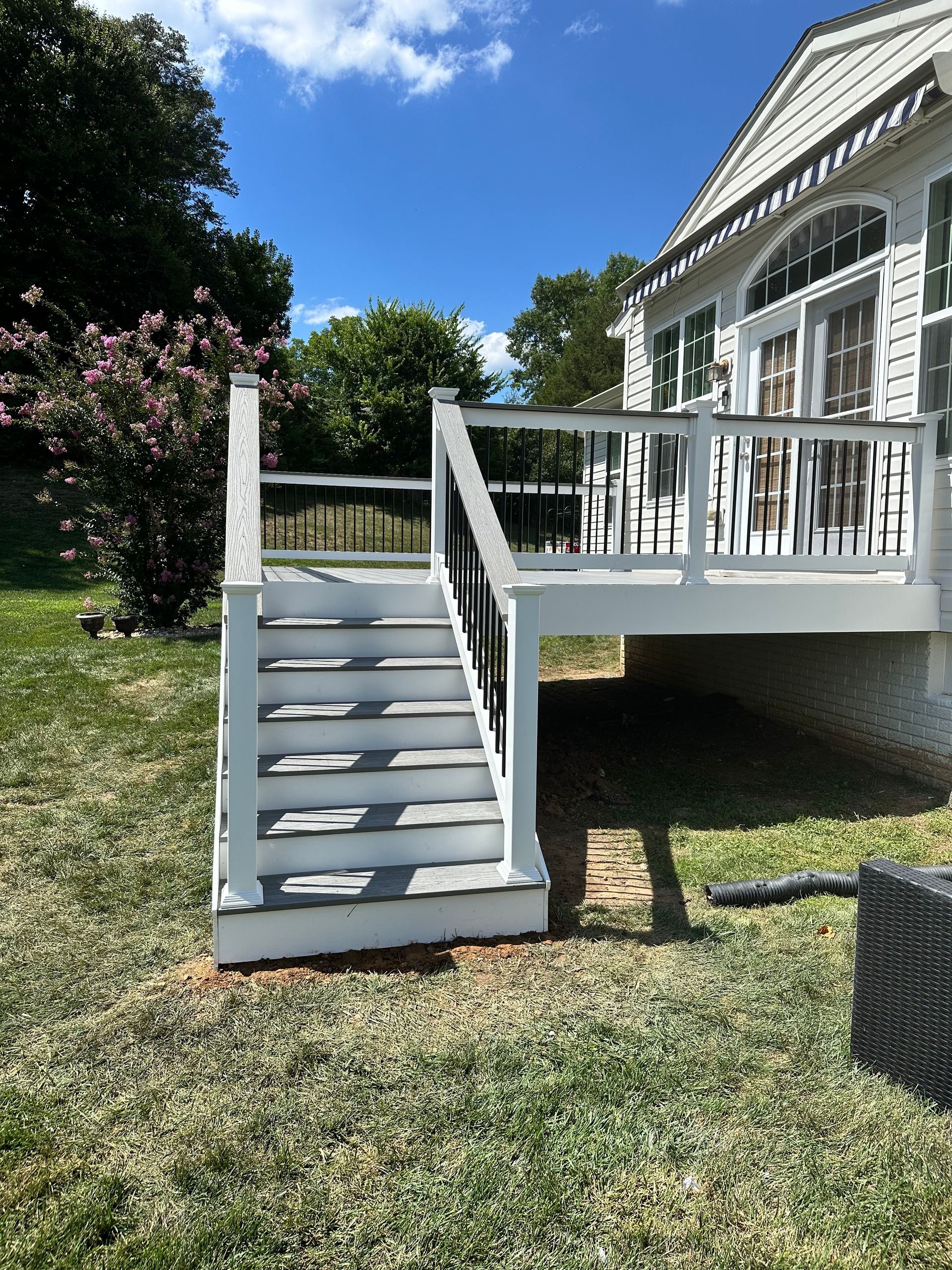 A white deck with stairs leading up to it in front of a house.