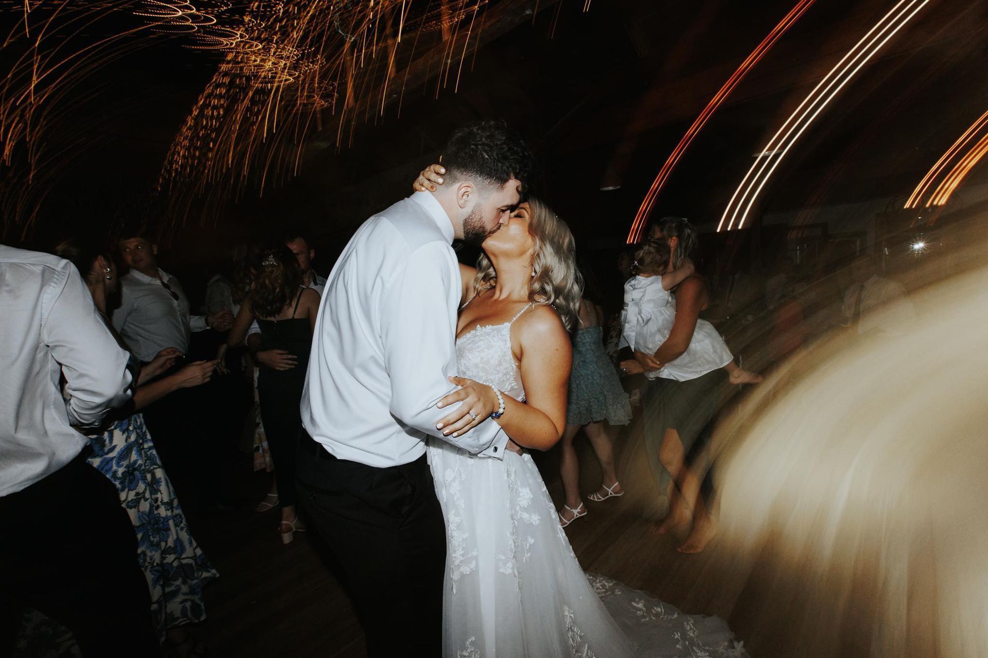 A bride and groom are kissing while dancing at their wedding reception.