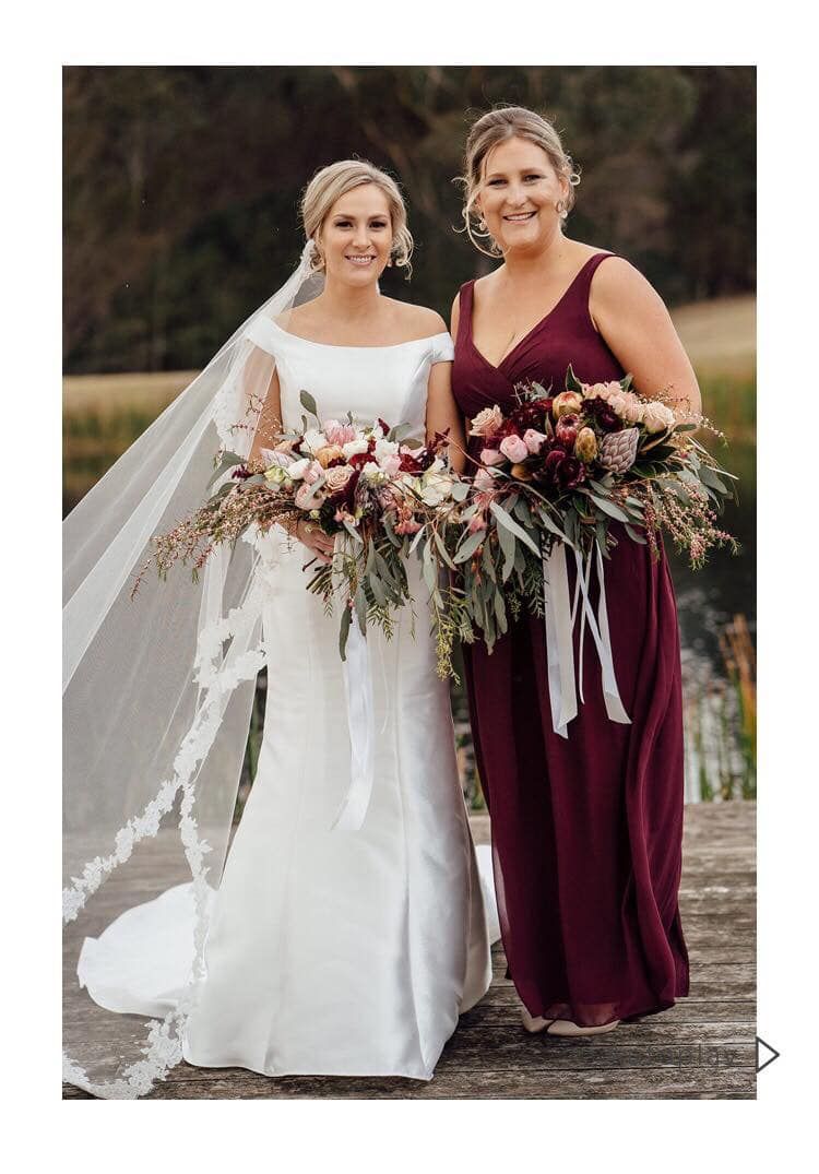 A bride and her bridesmaid are standing next to each other holding bouquets of flowers.