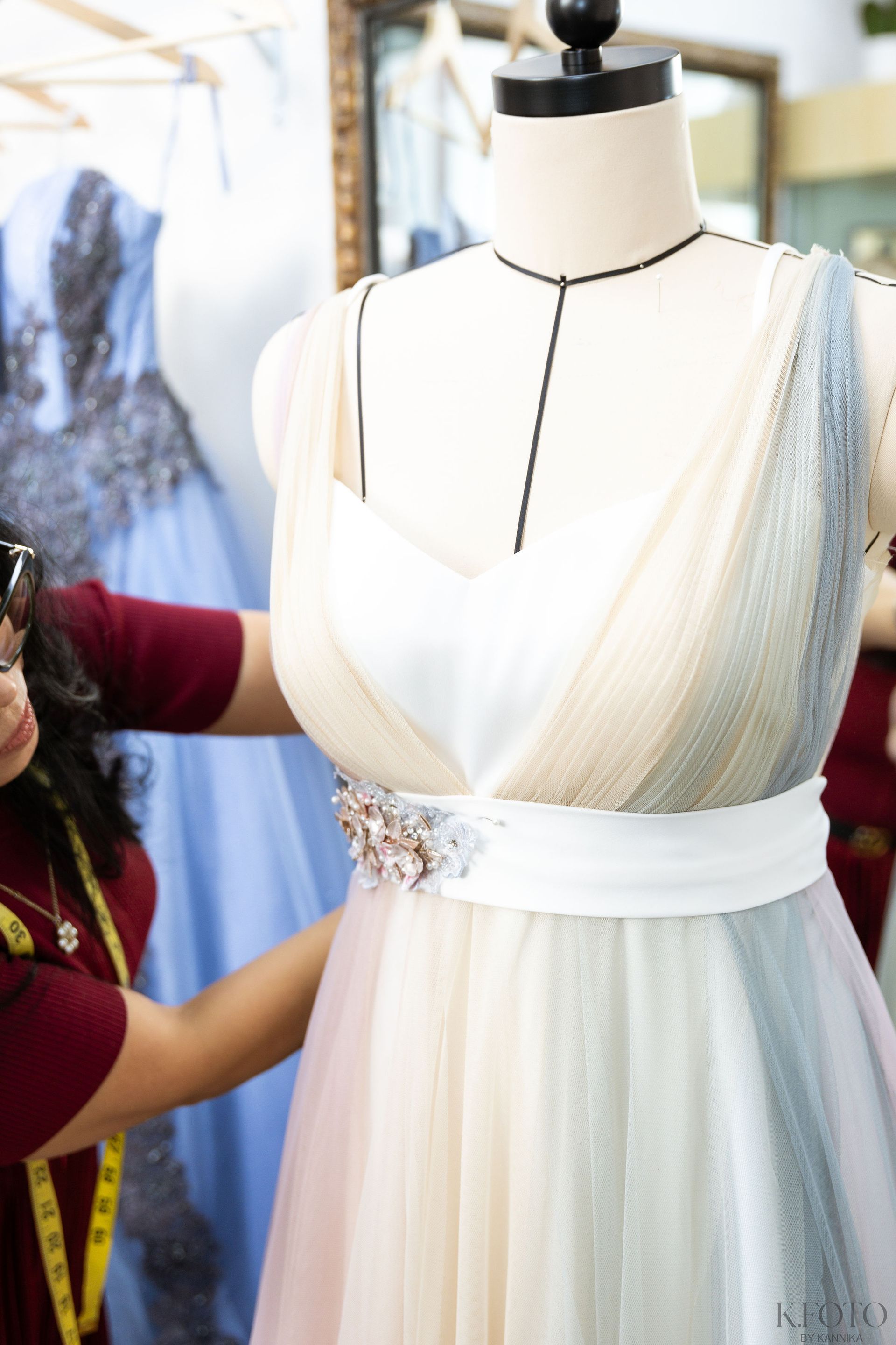 A woman is working on a dress on a mannequin