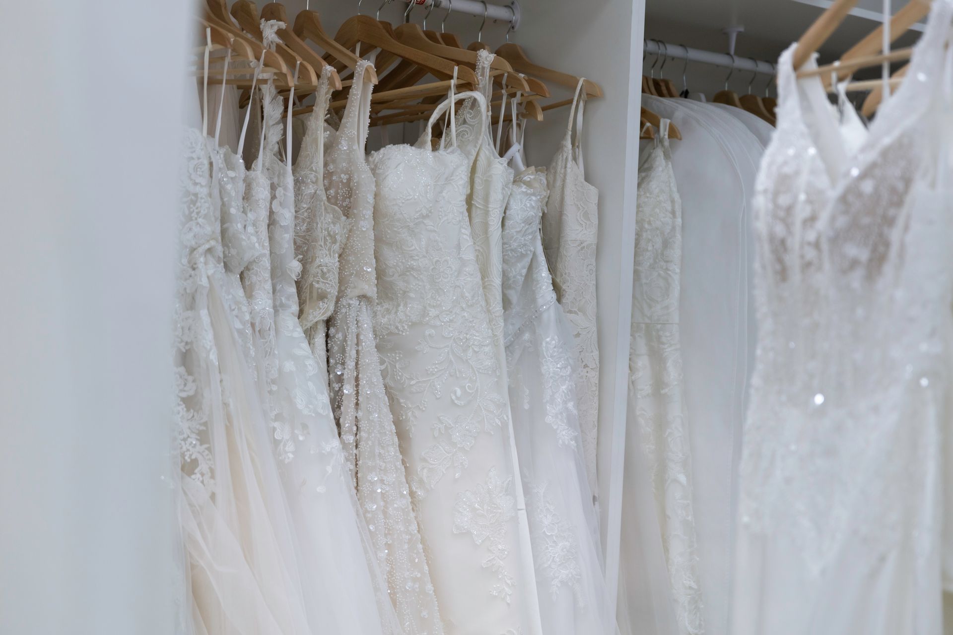 A closet filled with lots of white dresses hanging on hangers.