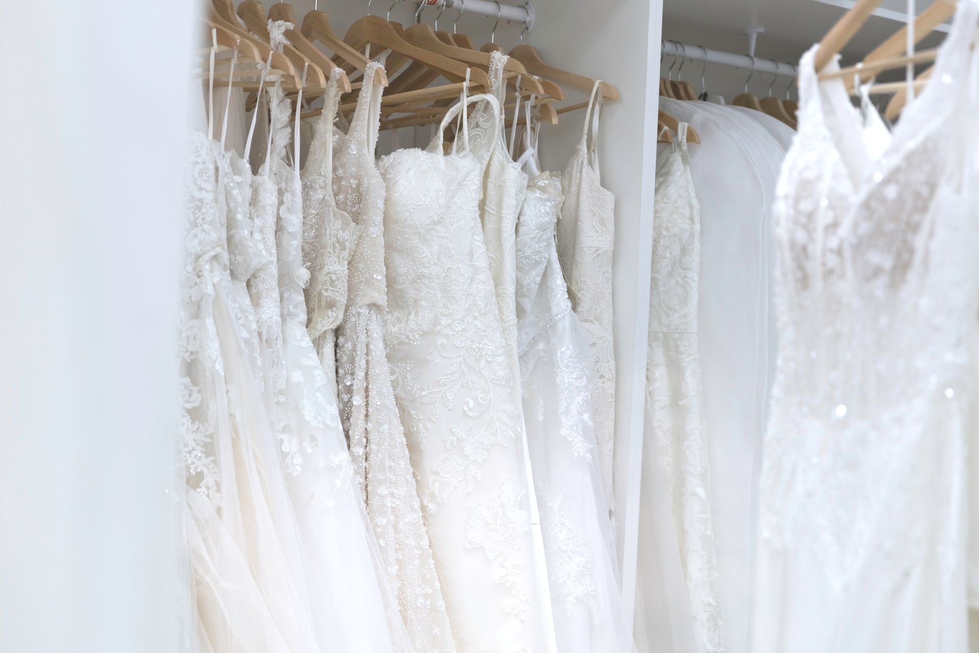 A closet filled with lots of white dresses hanging on hangers.