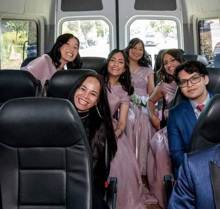 A group of people are sitting in a van and smiling
