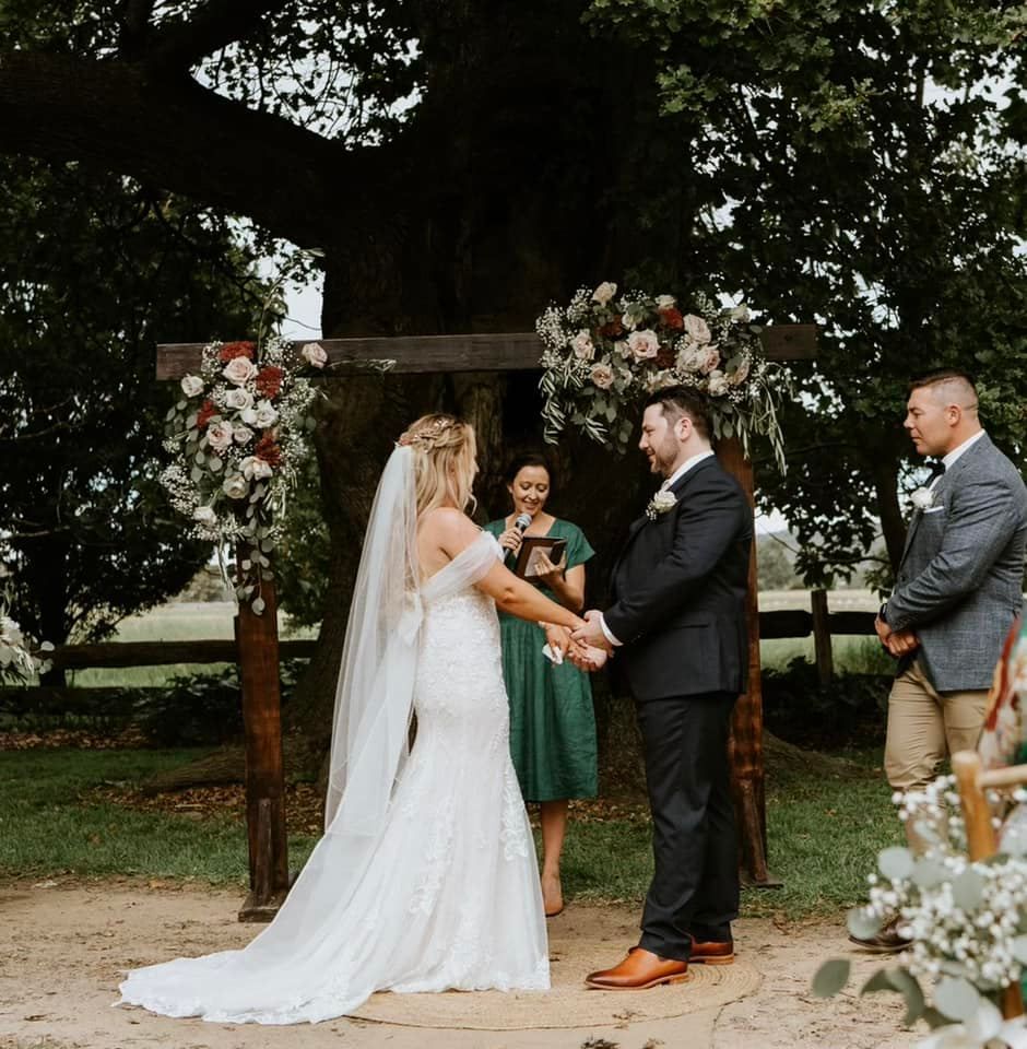 A bride and groom are holding hands during their wedding ceremony