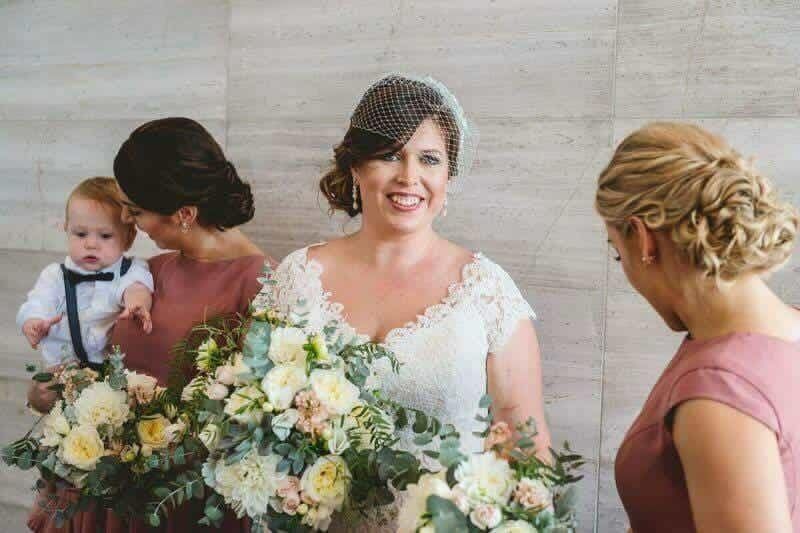 A bride and her bridesmaids are standing next to each other holding bouquets of flowers.