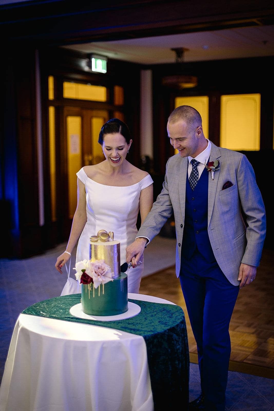 A bride and groom are cutting their wedding cake on a table.