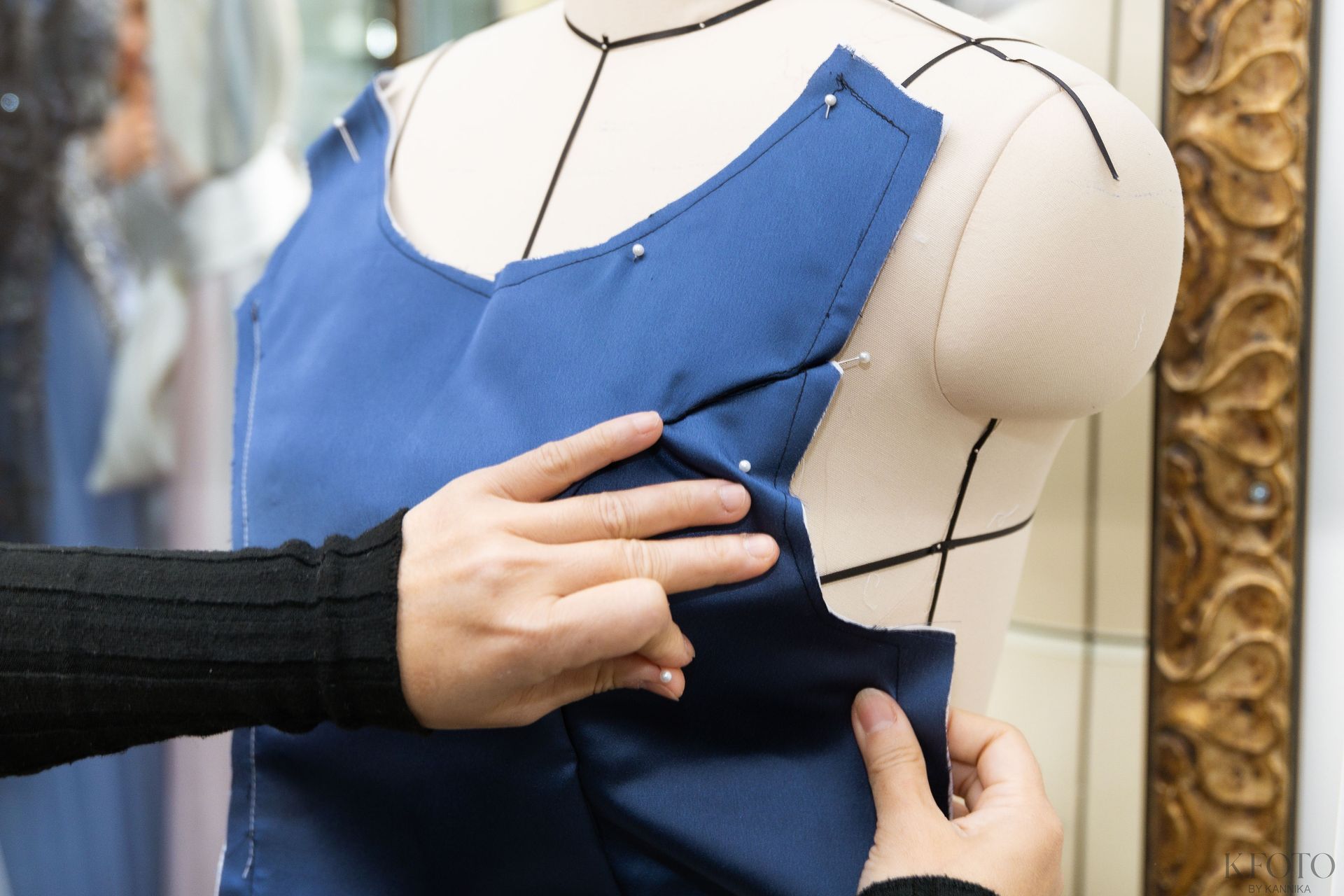A woman is helping a woman try on a wedding dress in front of a mirror.
