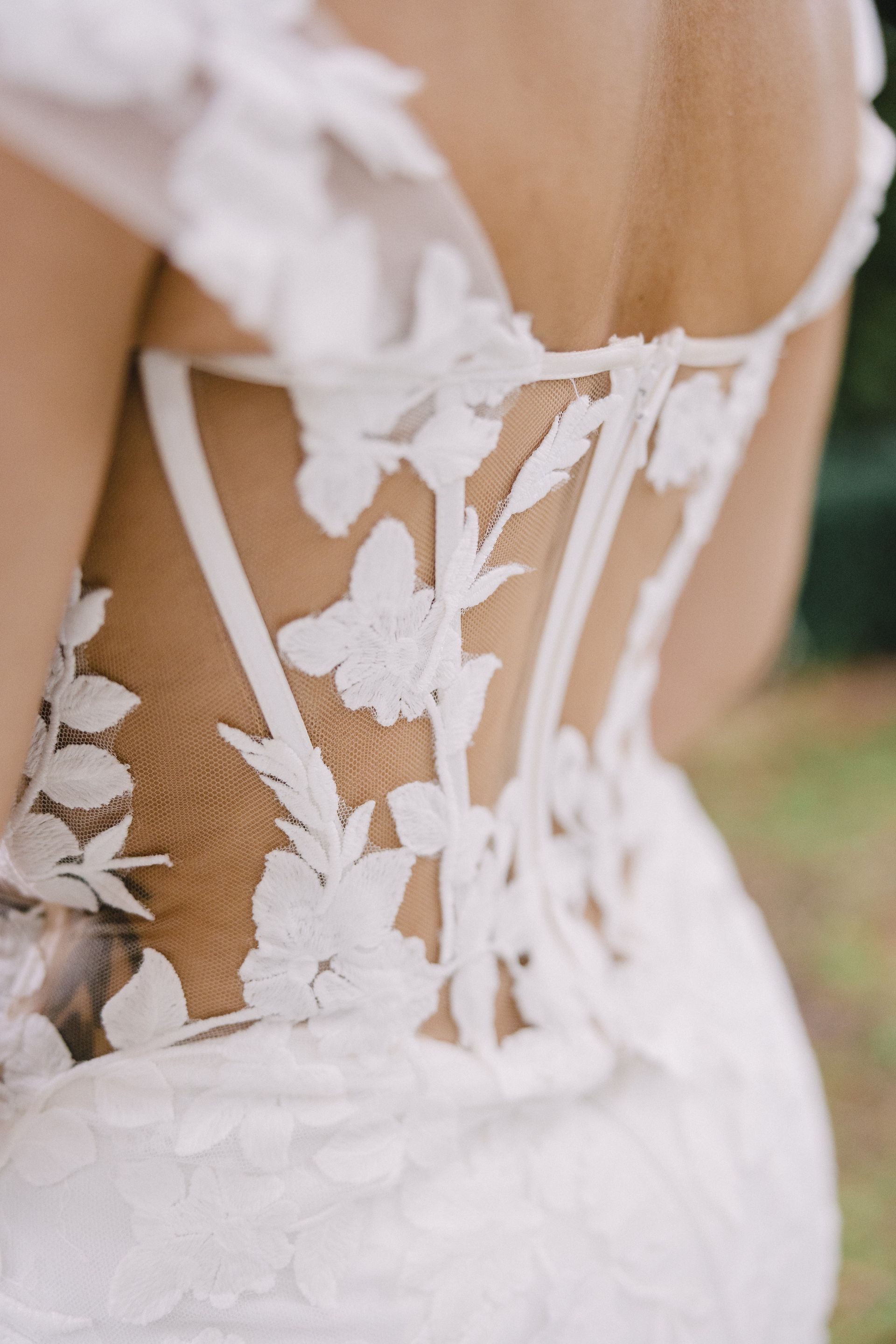 Close-up of a white lace wedding dress with floral embroidery and open back details