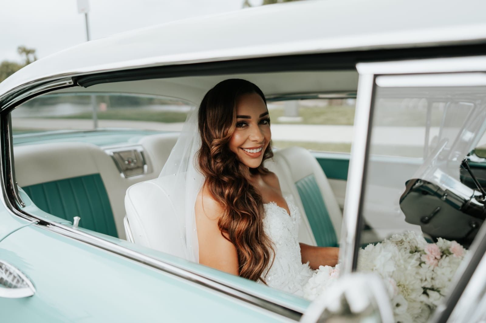 A bride is sitting in the back seat of a car.