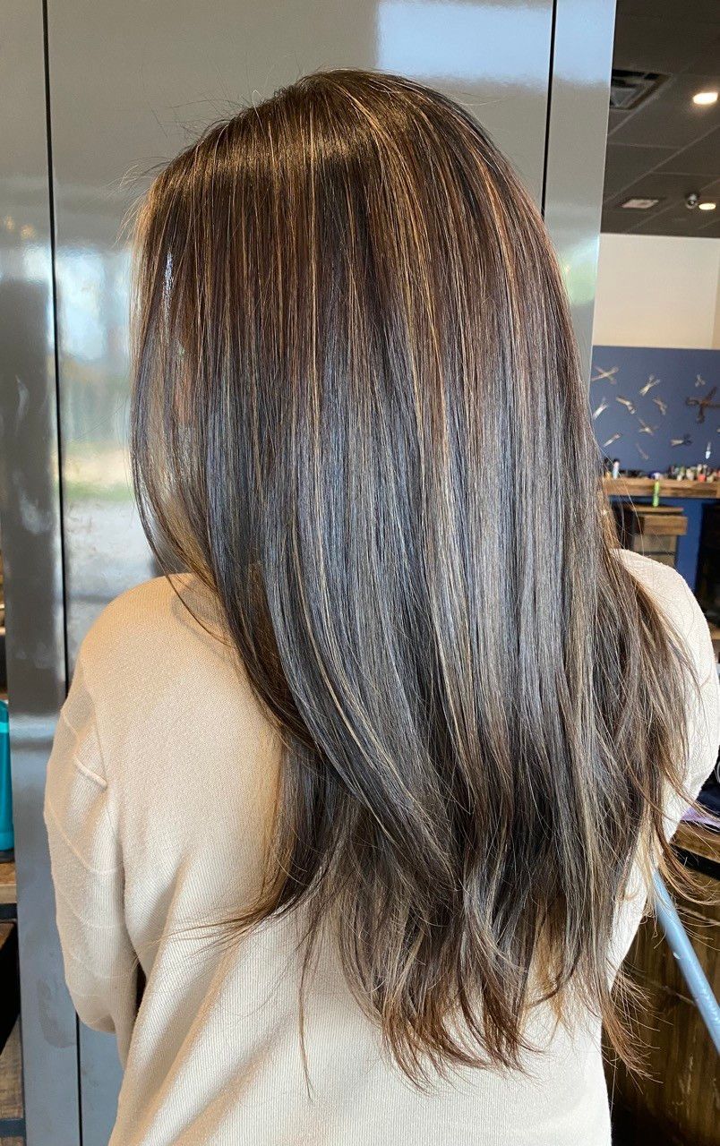 Woman with dark brown, highlighted hair. She's wearing a beige sweater. Shot from the back.