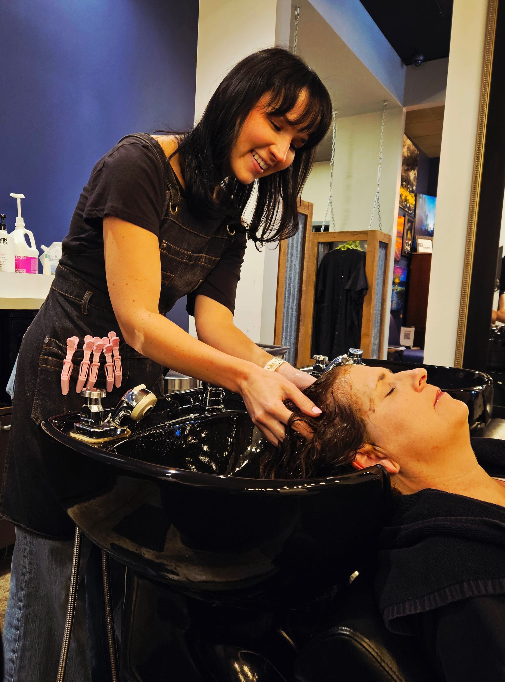 A stylist washes a customer's hair at a salon.
