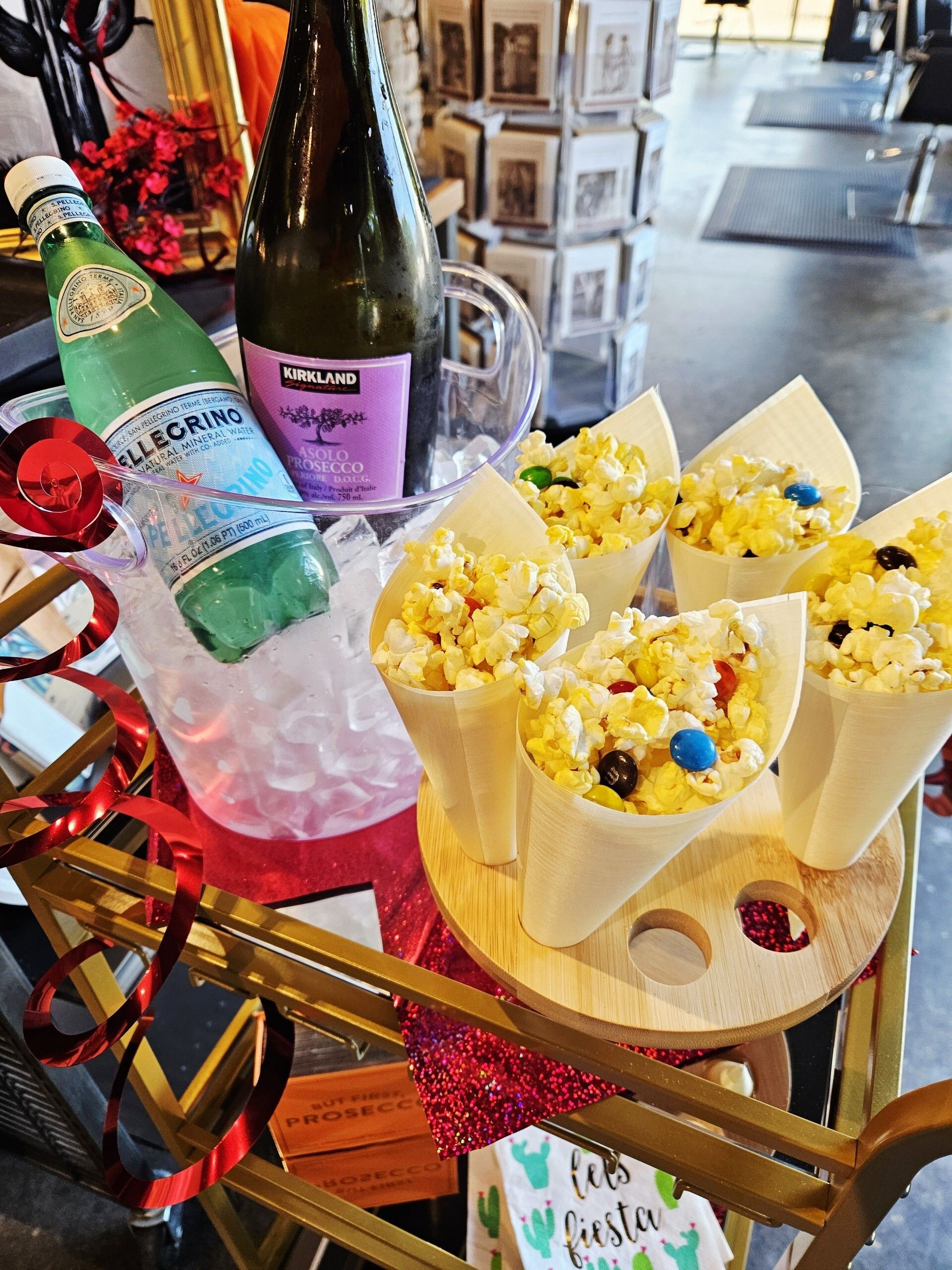 Table with popcorn cones, drinks in an ice bucket, and decorations.