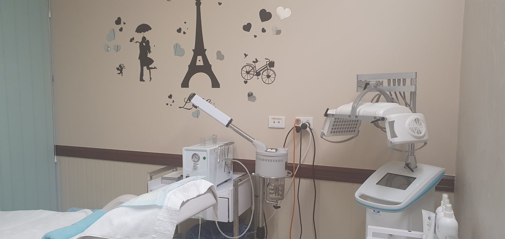Examination room with treatment bed, equipment, and medical supplies — Embrace Cosmetic Clinic in Bundaberg North, QLD