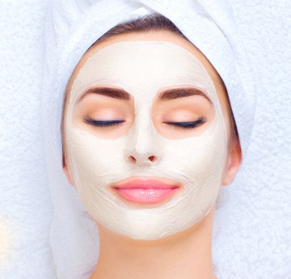 Woman With Facial Mask, Eyes Closed, Wrapped in a White Towel — Embrace Cosmetic Clinic in Bundaberg North, QLD