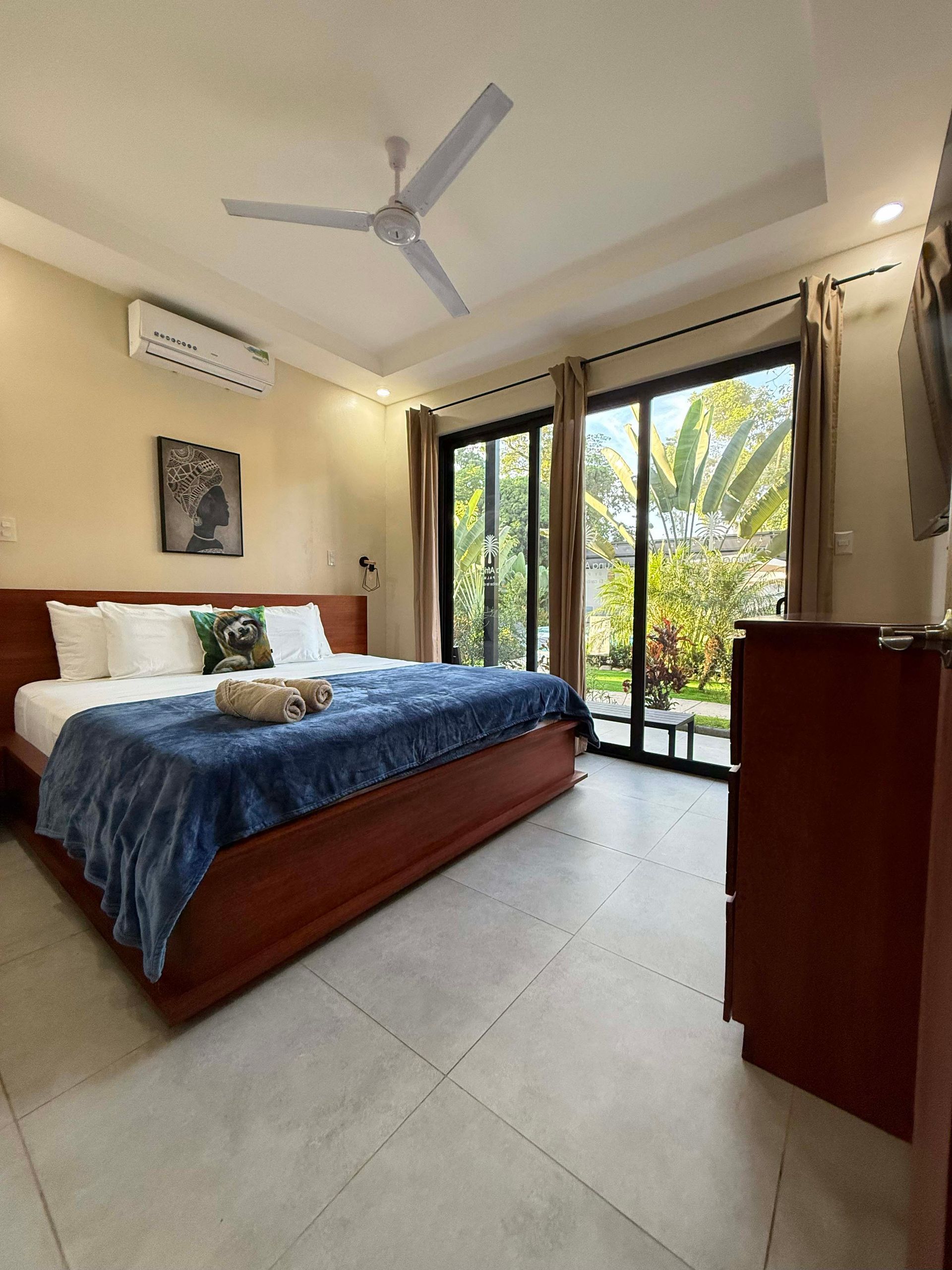 Bedroom with a king-size bed, sliding glass doors to a garden, and a ceiling fan.