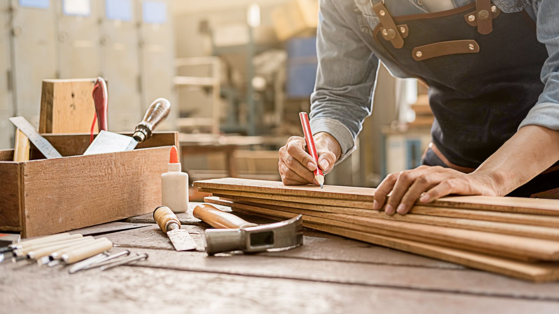 Carpenter measuring and marking wooden planks on a workbench with tools nearby