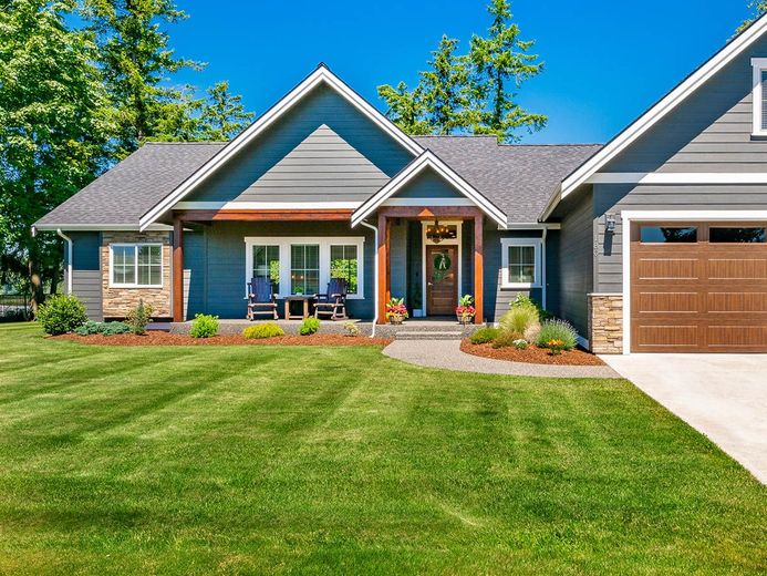A large house with a lush green lawn and a garage.