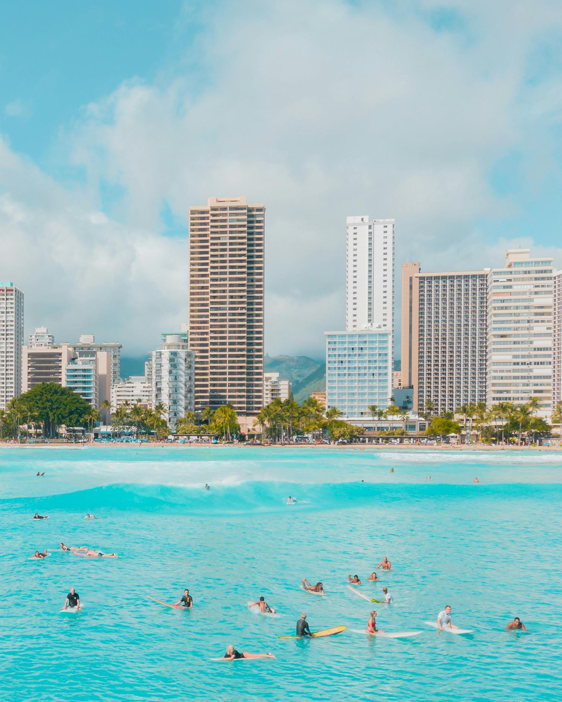 Ocean with surfers and skyline of buildings on a sunny day in Waikiki, Hawaii.
