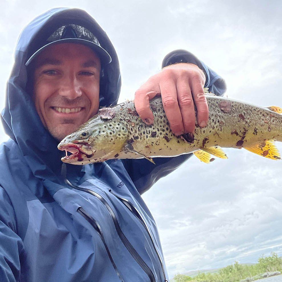 Espen Aulie viser frem en fisk han har fisket på teambuilding-tur