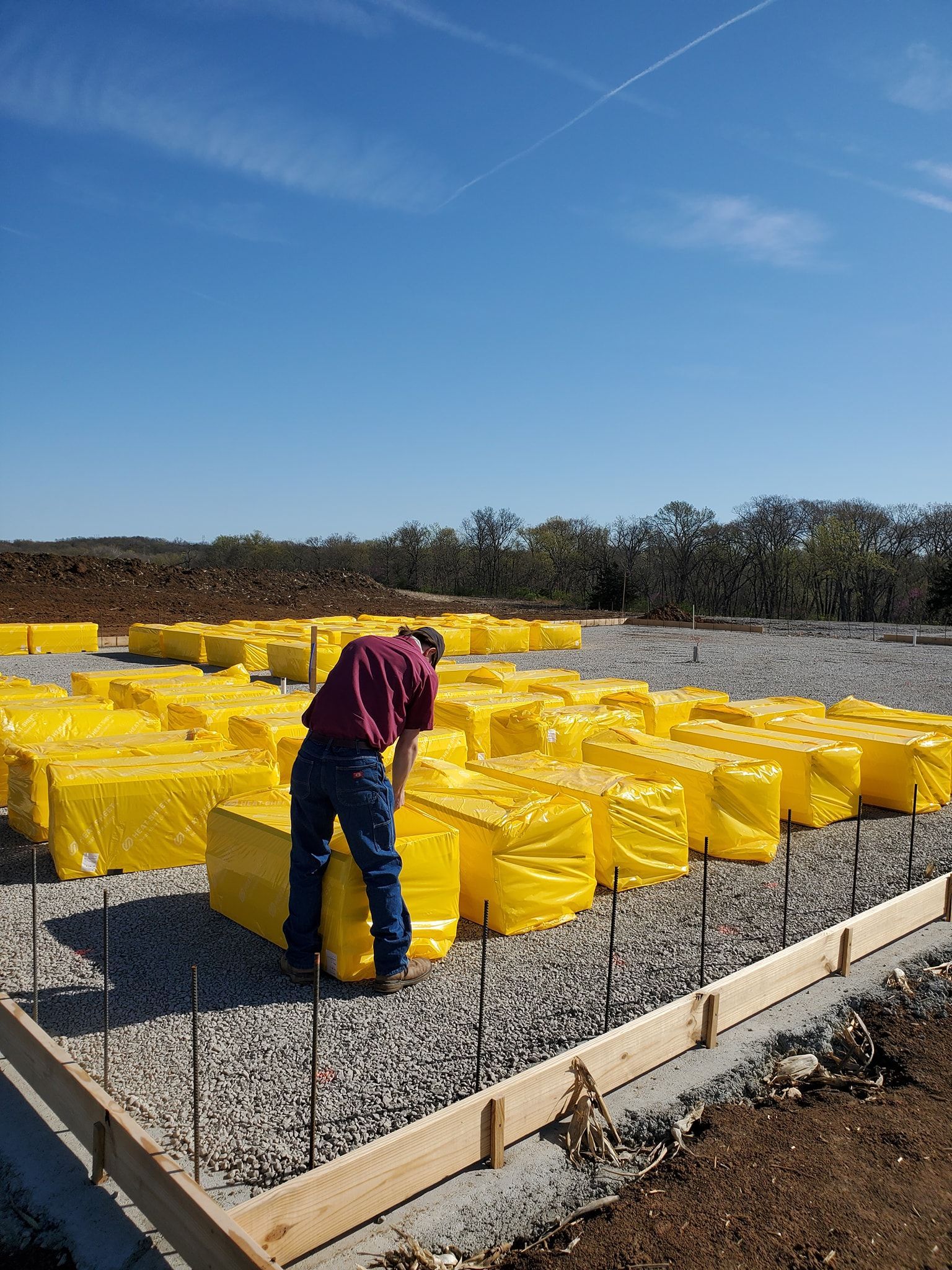 A man is working on a construction site surrounded by yellow bags.
