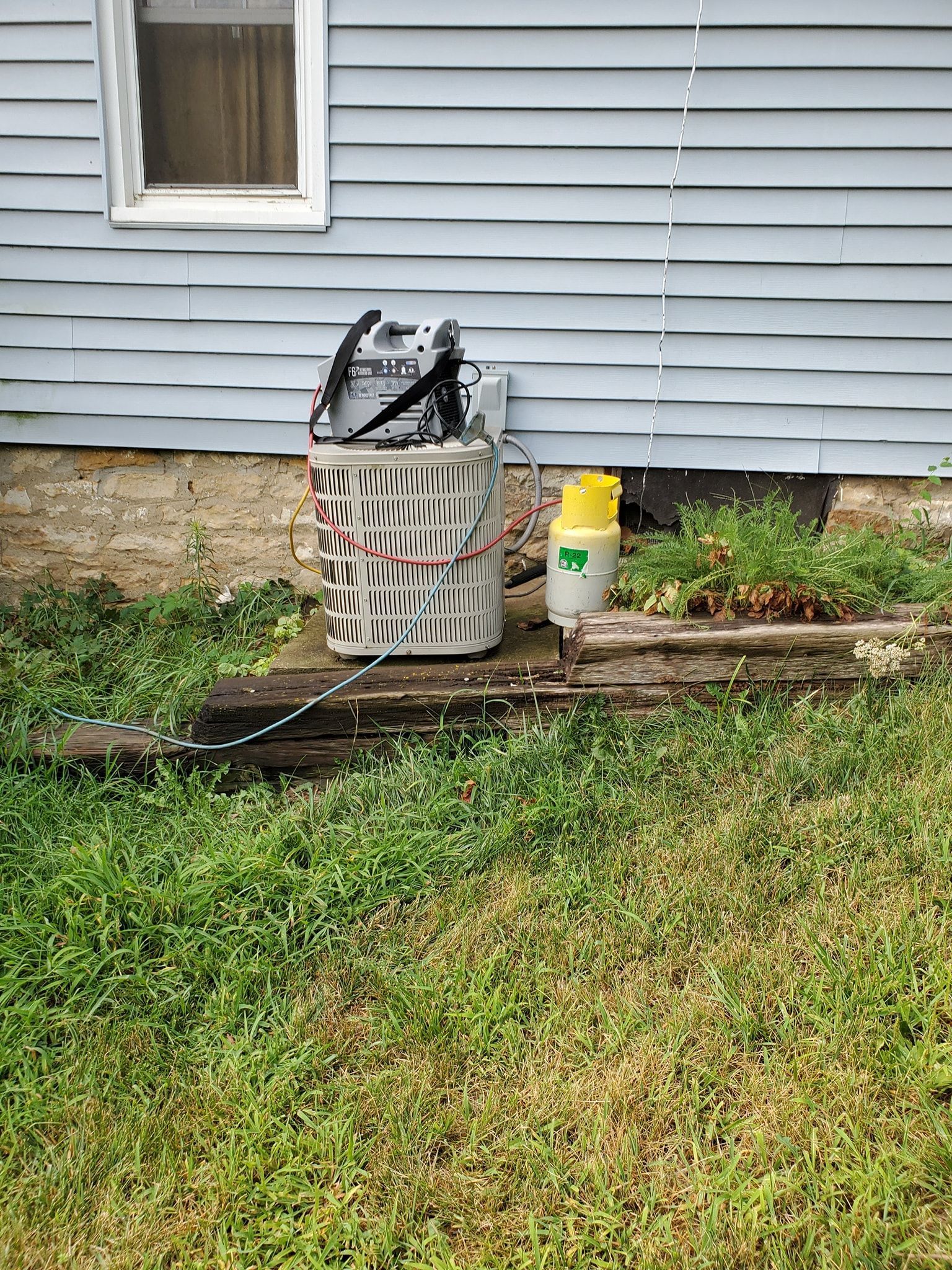 A tool bag is sitting on the ground in front of a house.