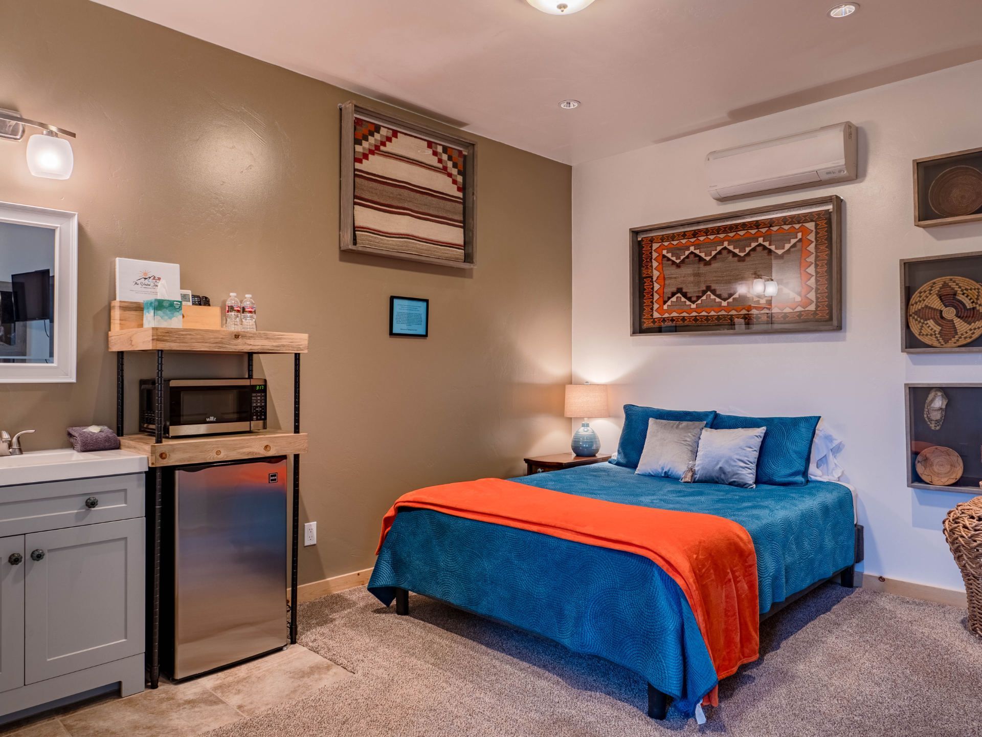 A bedroom with a bed , sink , microwave and refrigerator.