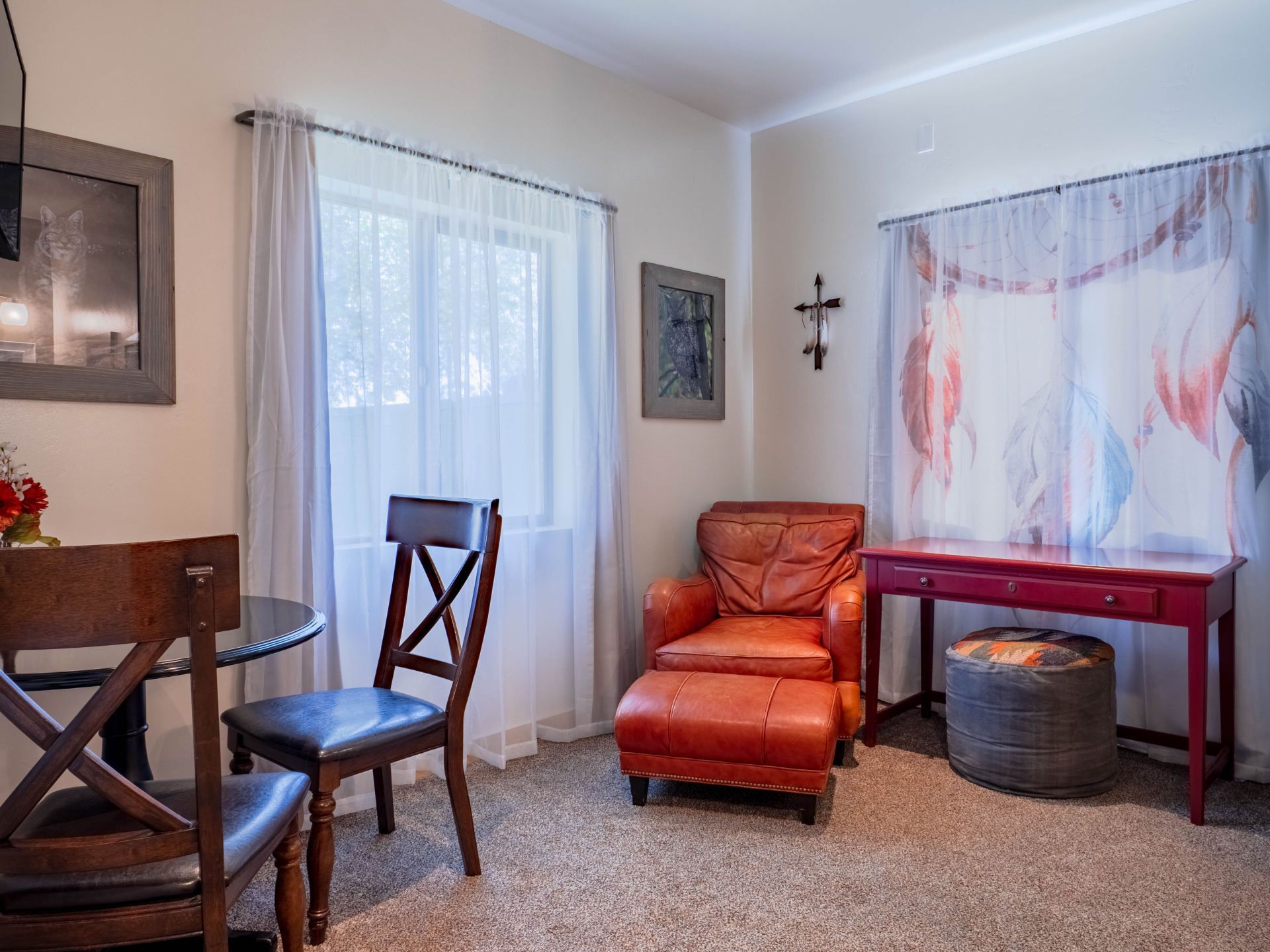 A living room with a red chair , ottoman , table and chairs.