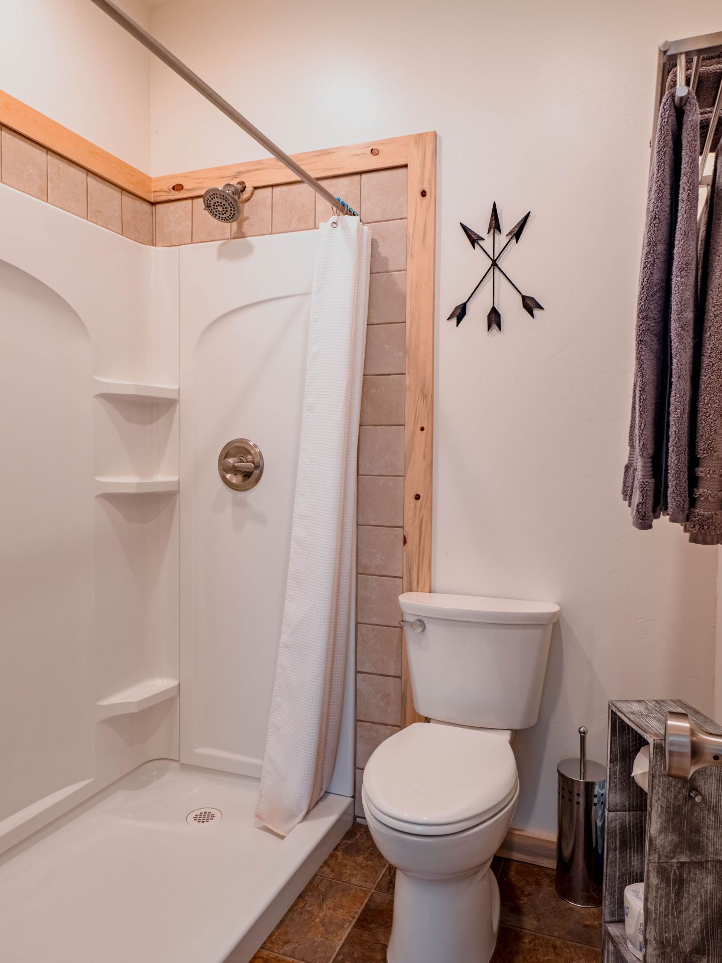 A bathroom with a toilet , shower and arrows on the wall.