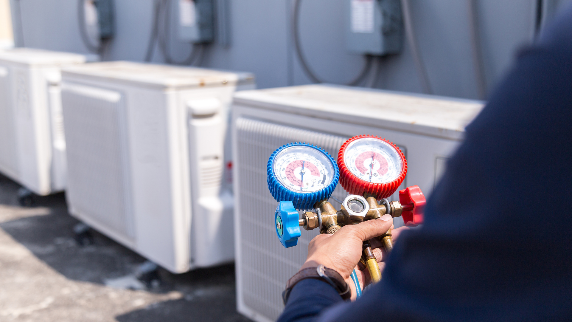 HVAC technician using gauges to service an outdoor air conditioning unit.