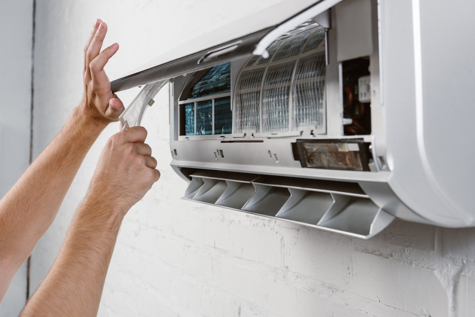 Person cleaning an air conditioner. They are opening the unit to access the filters.
