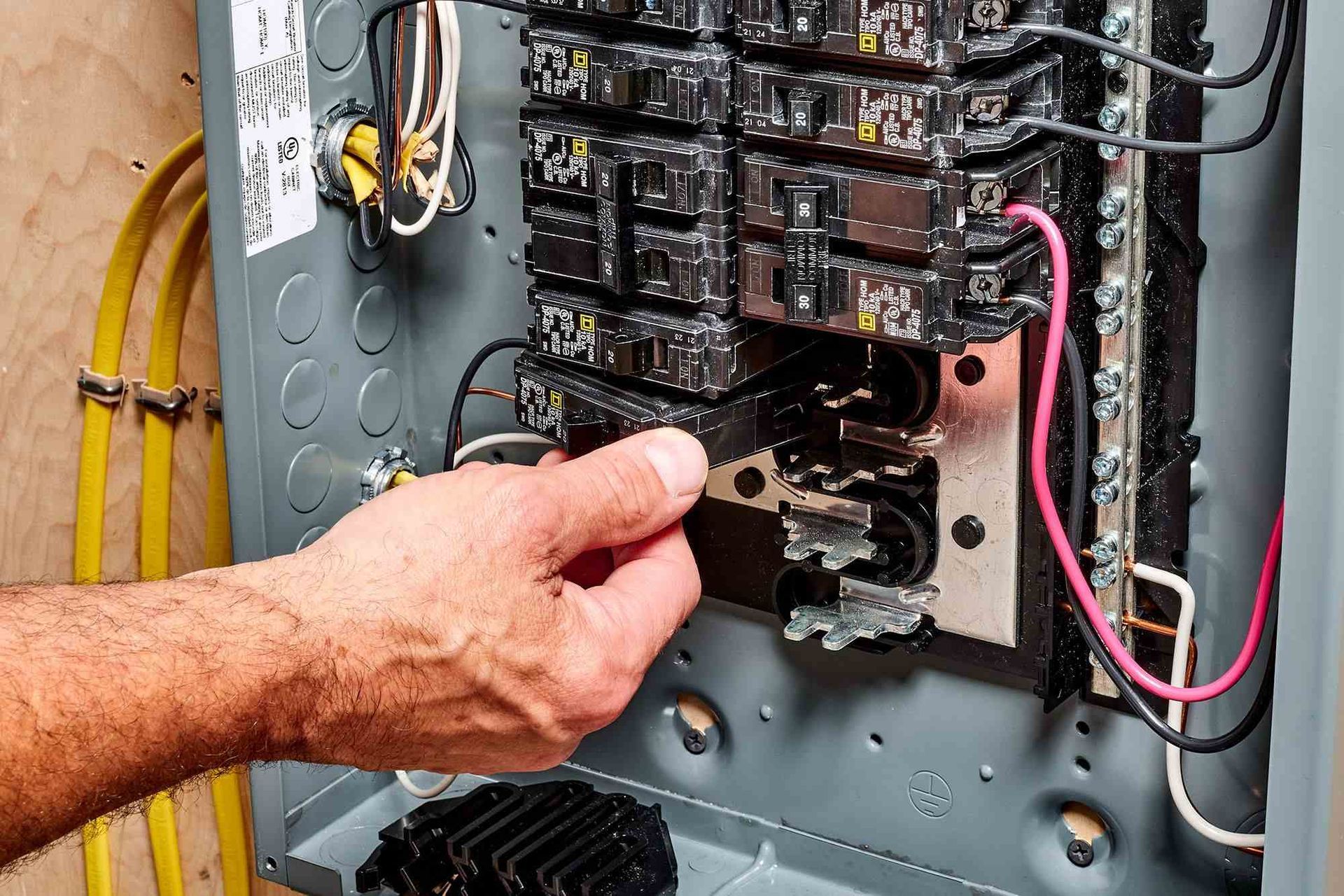 Person installing a circuit breaker in an electrical panel.