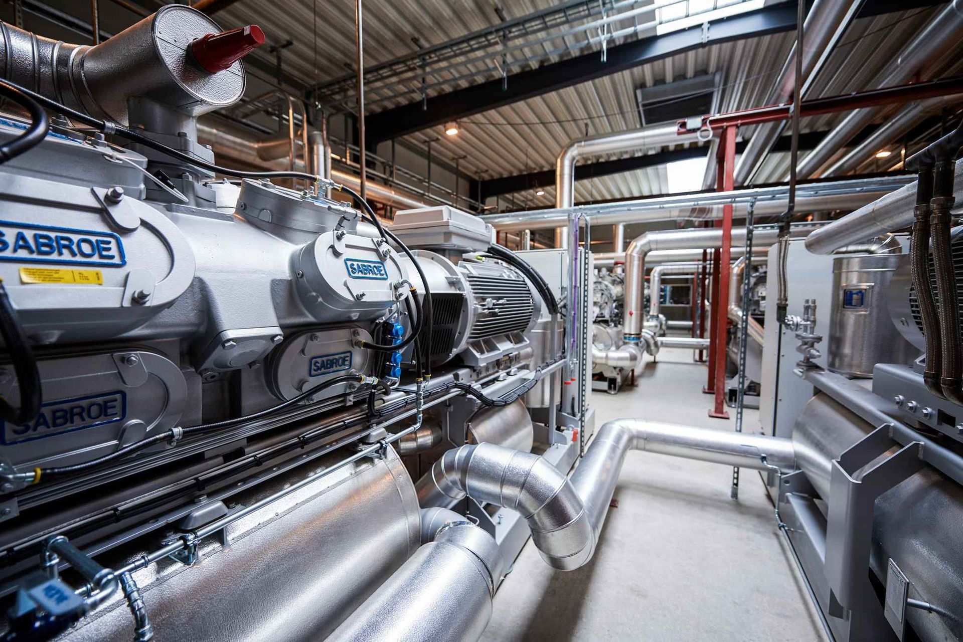 Large industrial refrigeration machinery in a facility with pipes and insulated tubing.