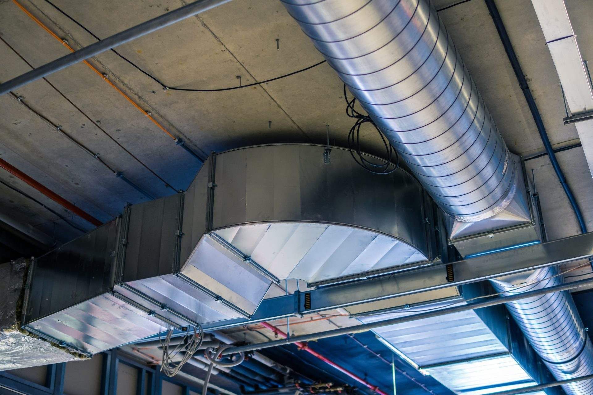 HVAC ductwork on a ceiling, metal and angled, with curved and straight sections.