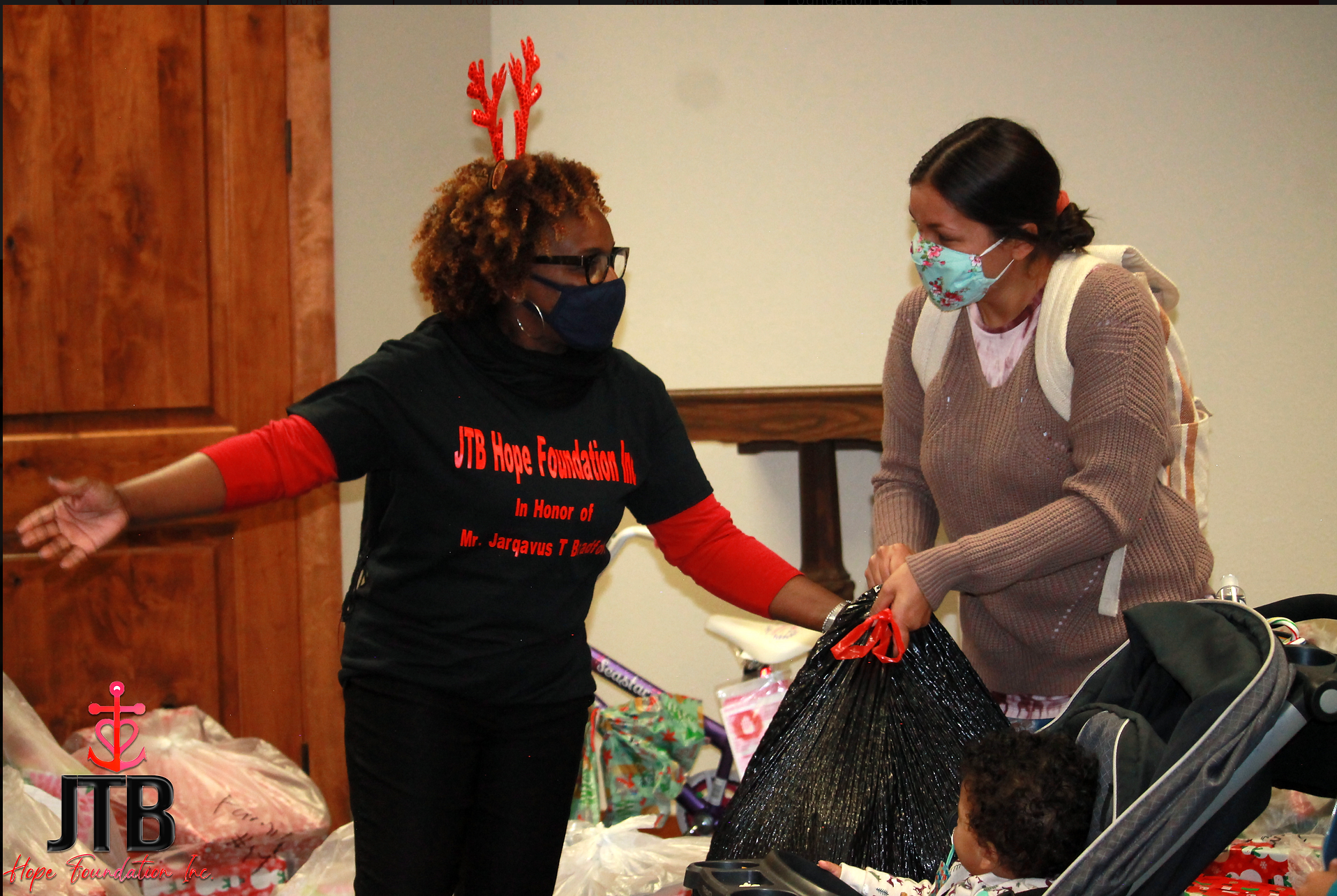 Two women wearing face masks are standing next to a child in a stroller ..
