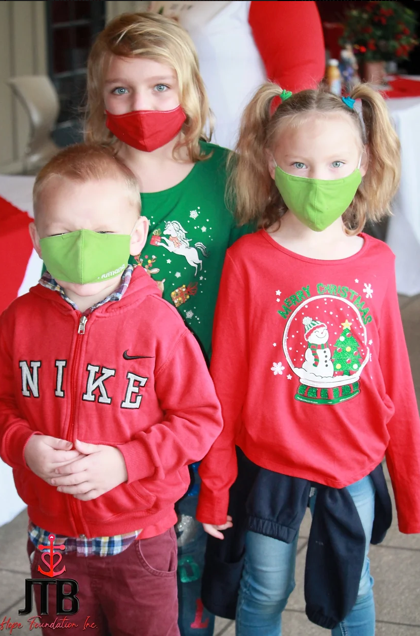 A boy wearing a nike sweatshirt stands next to two girls wearing face masks