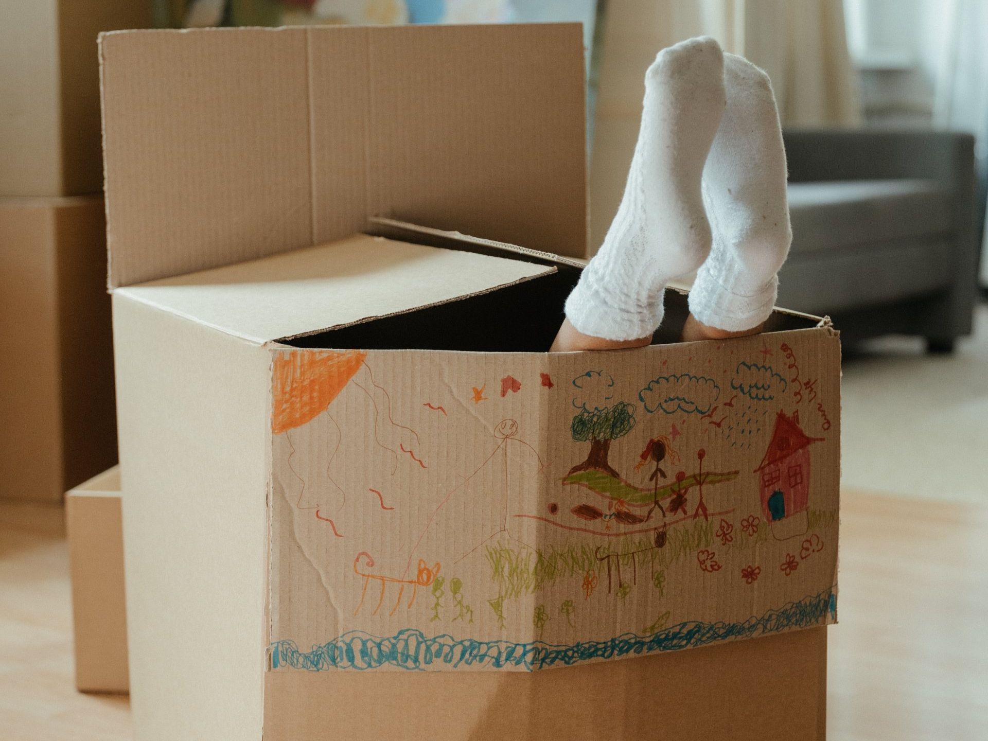 A person 's feet are sticking out of a cardboard box.