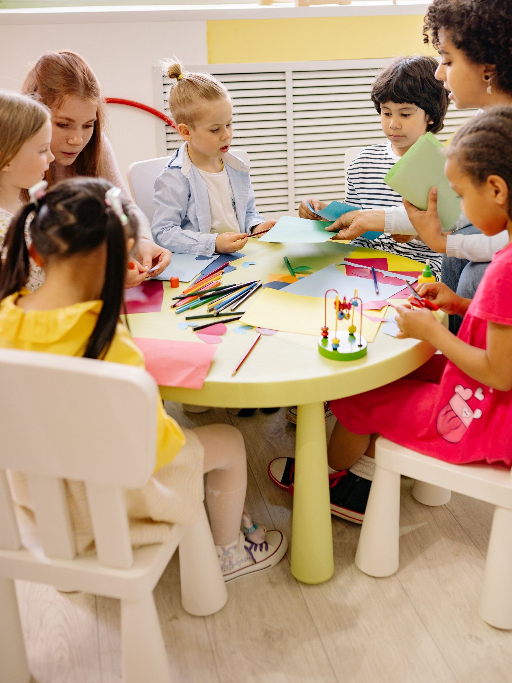 A group of children are sitting around a table playing with toys.