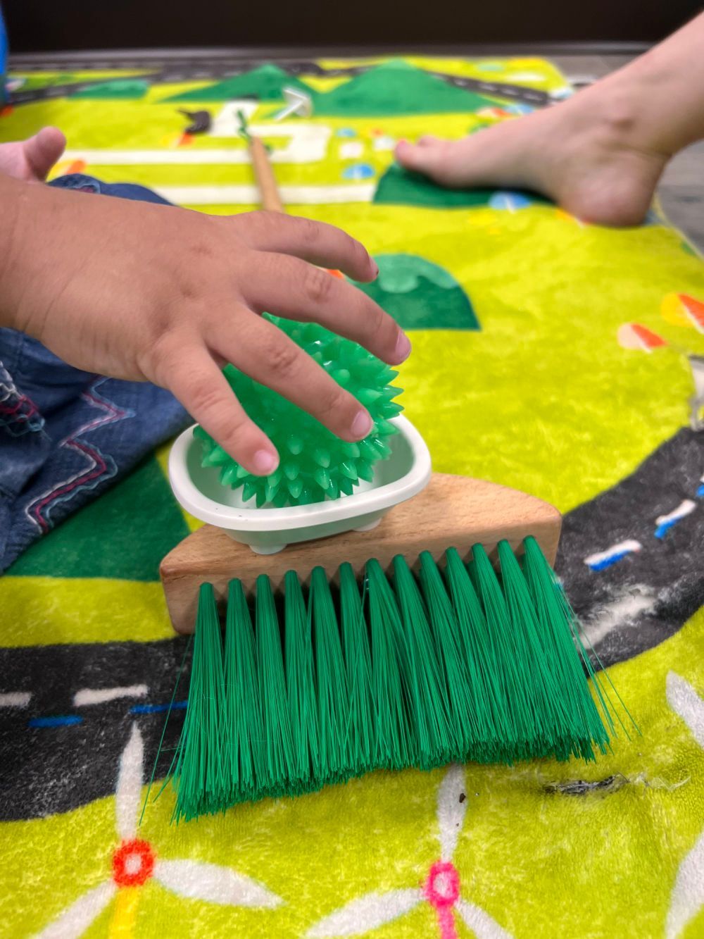 A child is playing with a green brush and a green ball.