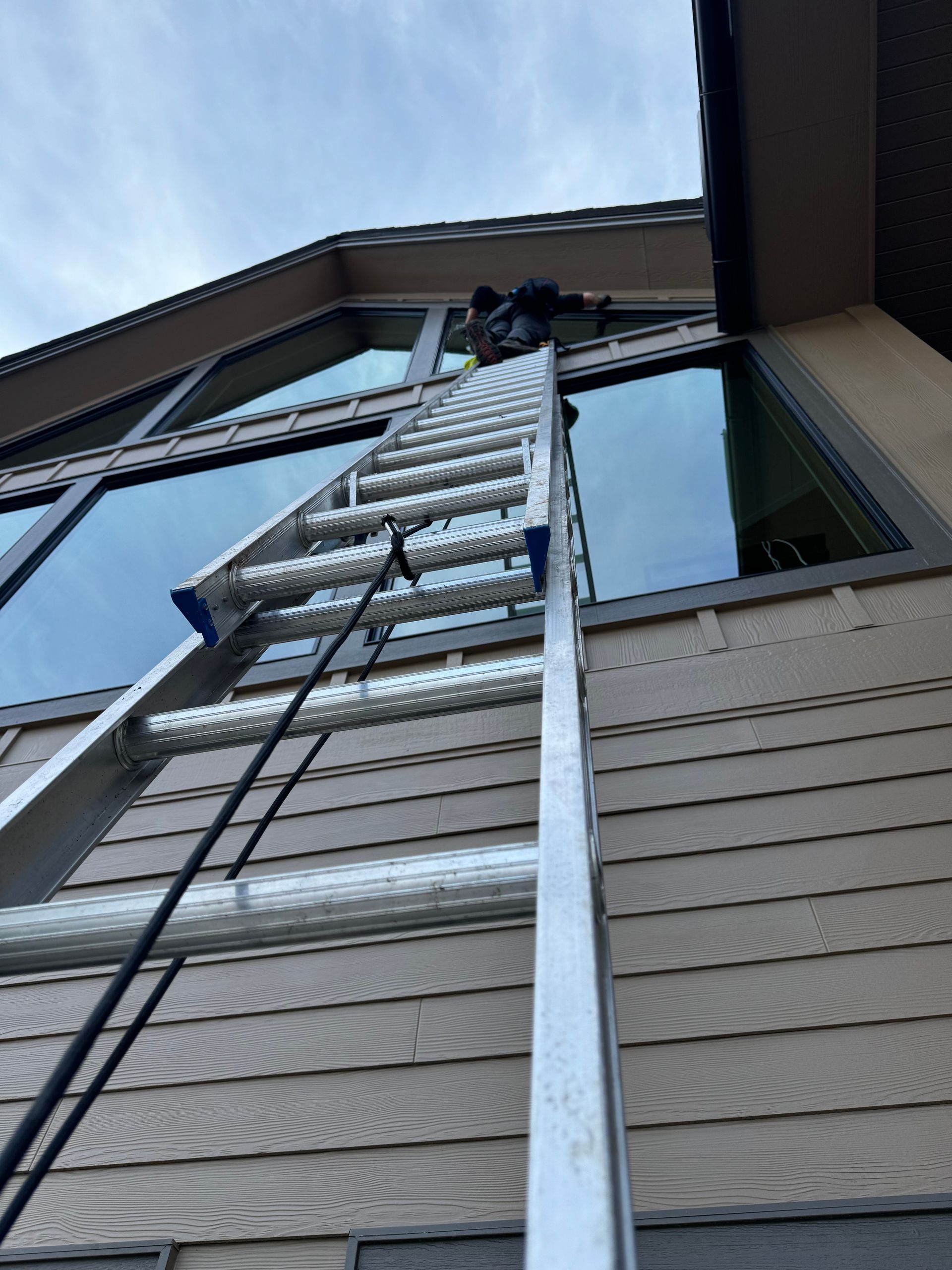 A man is standing on a ladder on the side of a building.