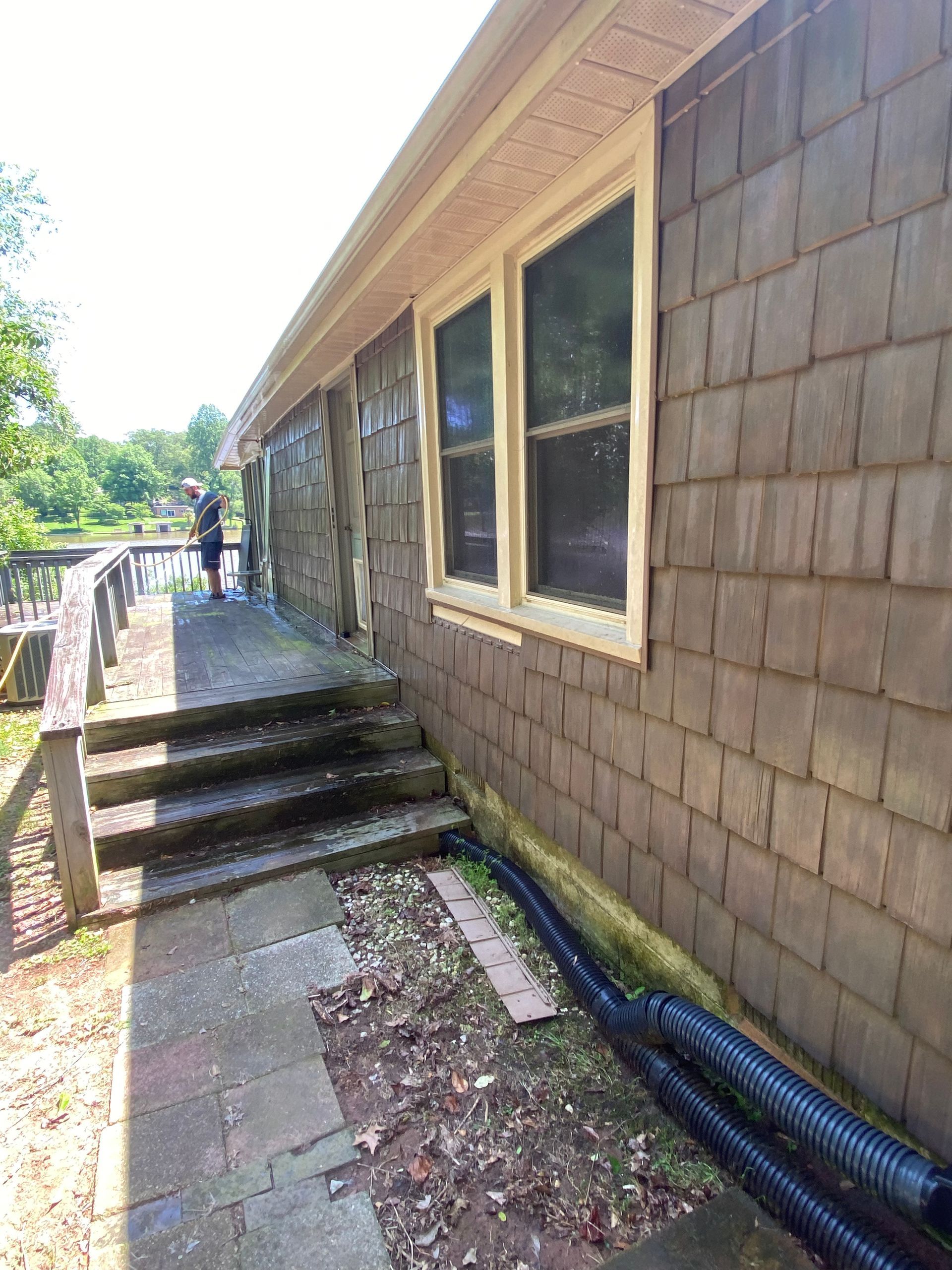 A man is standing on the side of a house with stairs leading up to it.