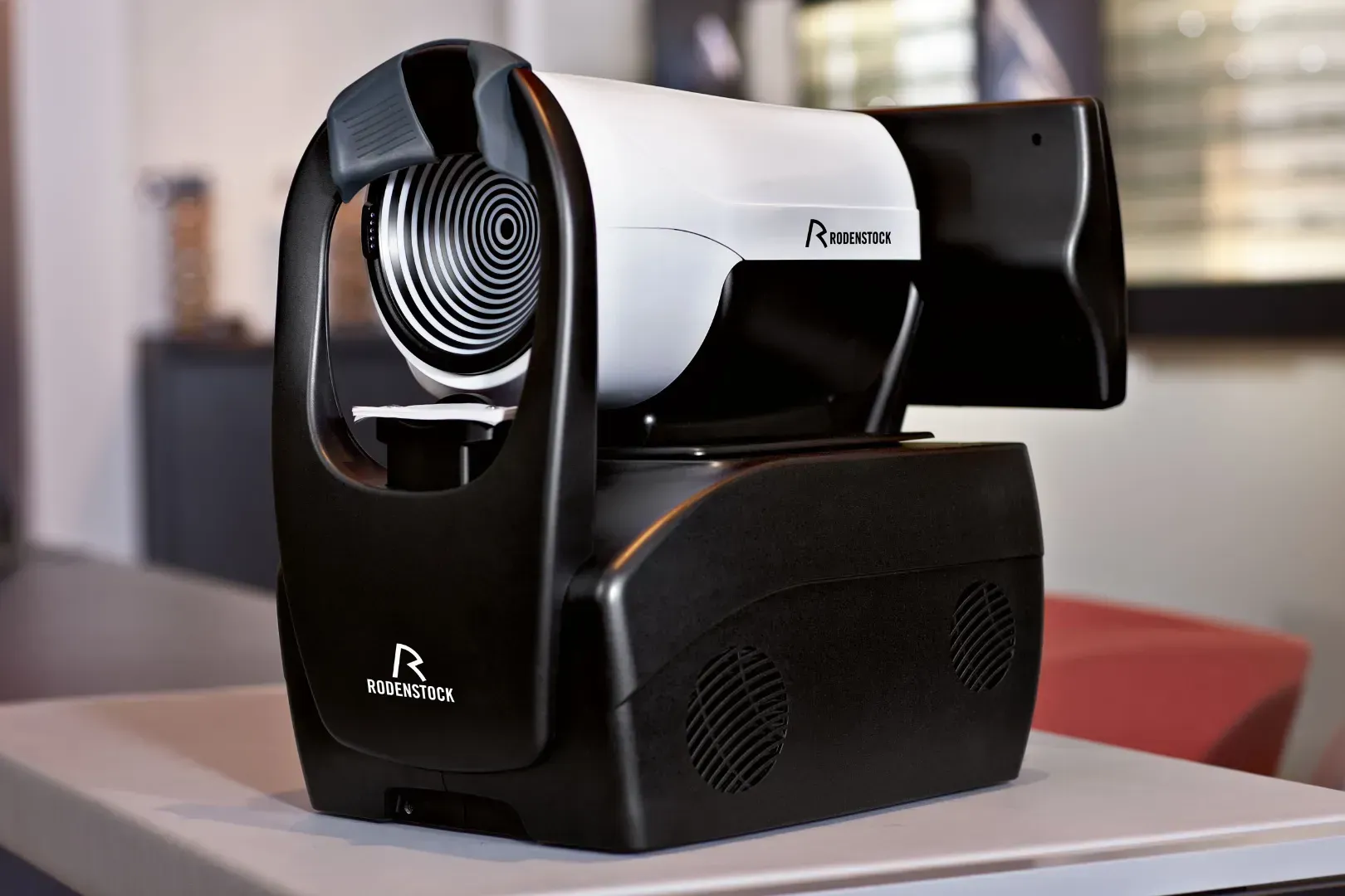 Briller udstillet; blå og lilla stel på en hvid overflade med en dekorativ vase og grønt.