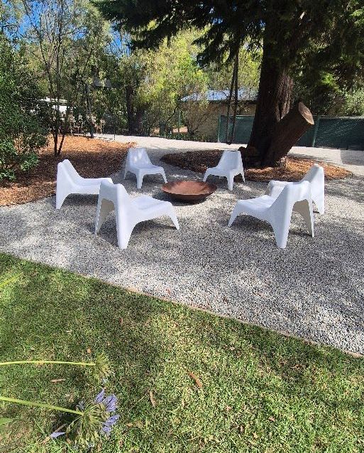 A group of white chairs are sitting around a fire pit.