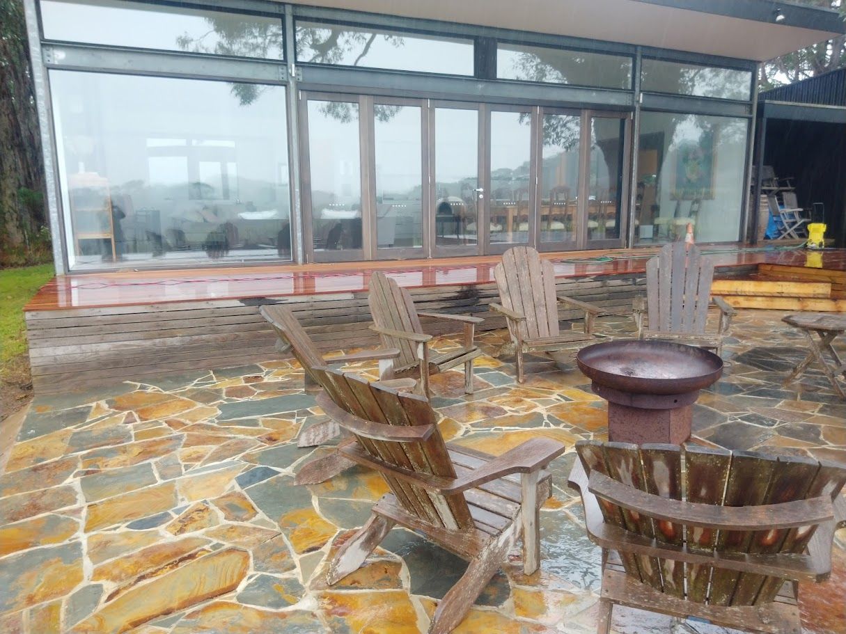 A patio with chairs and a fire pit in front of a house.