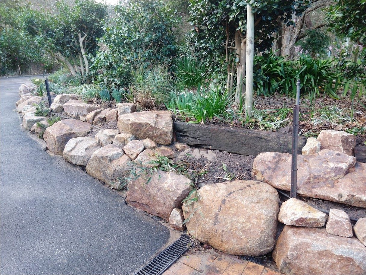 A stone wall along the side of a road in a garden.